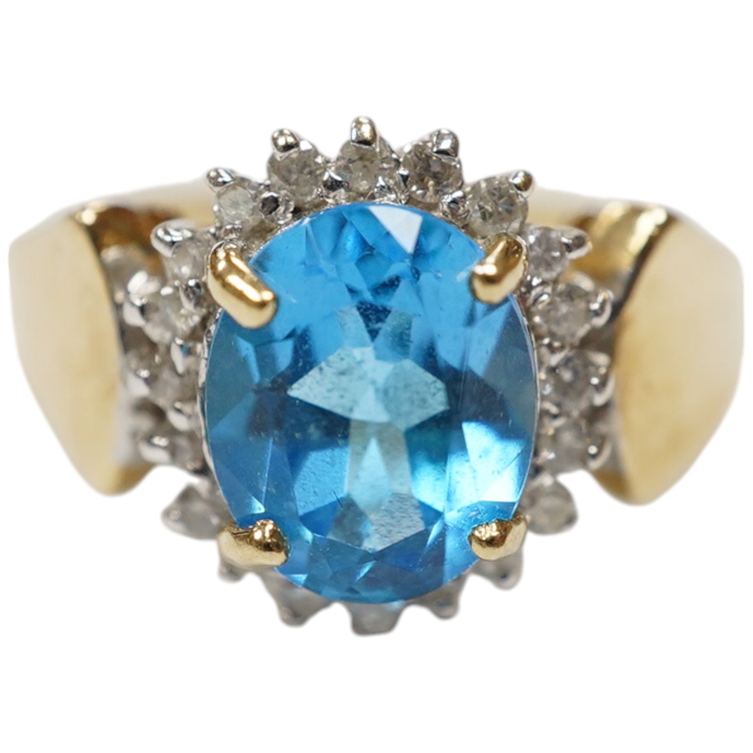 A modern 14k and oval cut blue topaz set dress ring, bordered with diamonds, size R, gross weight 4.7 grams. Condition - fair to good.